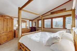 Ein Zimmer mit einem Himmelbett, Holzmöbeln und großen Fenstern.