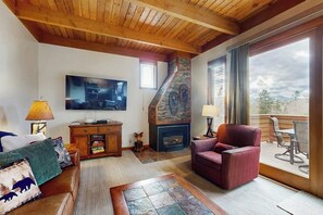 Ein Wohnzimmer mit Kamin, Fernseher, Sofa und einem Essbereich mit Blick.