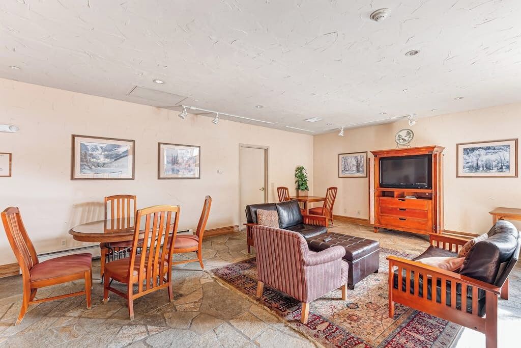 A living room with a stone floor, wooden furniture, a television, and framed pictures on the walls.