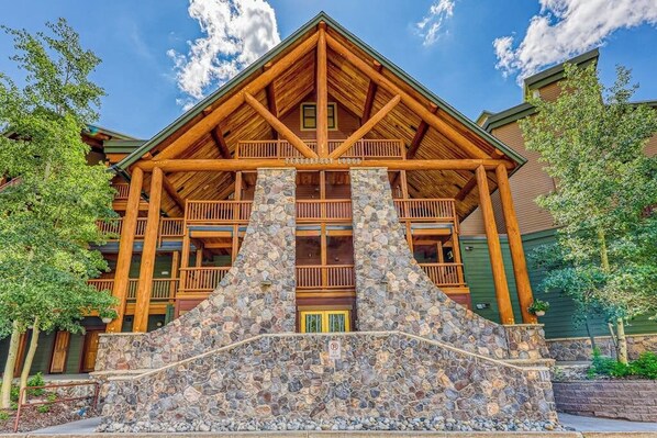 Ein Chalet mit einer Steinfassade, Holzbalkonen und blauem Himmel.
