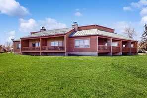 A two-story wooden house with a covered porch and a fenced yard. - Dog-friendly condo w/ covered porch & views - near golf, lakes & ski (Pagosa Springs)