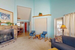 Una sala de estar con chimenea, dos sillones azules, un sofá y una lámpara.
