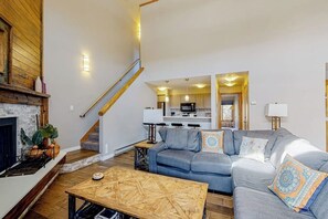 Ein Wohnzimmer mit Kamin, einer Couch, einem Couchtisch und einer Treppe, die zur Küche führt.