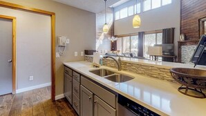 Une cuisine moderne dotée d’un grand îlot central, d’un évier double et de luminaires suspendus.