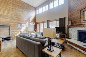 Ein modernes Wohnzimmer mit einem Ecksofa, einem Fernseher und einem Kamin.