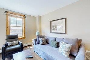 A living room with a grey sofa, a black leather chair, a small table, a lamp, and a framed picture on the wall. - Newly renovated mountain escape with pool, hot tub, WiFi & easy slope access (Keystone)