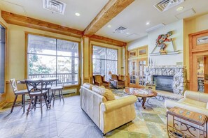 A spacious living area with a fireplace, large windows, and a stone accent wall. - Newly renovated mountain escape with pool, hot tub, WiFi & easy slope access (Keystone)