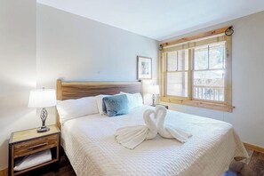 A neatly made bed with a swan towel design, a bedside lamp, and a window with a view. - Newly renovated mountain escape with pool, hot tub, WiFi & easy slope access (Keystone)