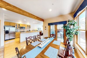 Una cocina moderna con armarios de madera, una isla central y un comedor con una mesa larga y sillas.