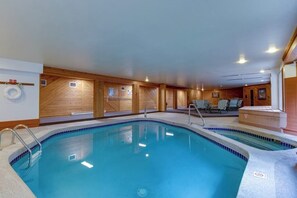 An indoor swimming pool with a tiled edge, wooden walls, and a seating area with chairs. - Ski-in/ski-out home with pool, hot tub, sauna, washer/dryer, & private balcony (Keystone)