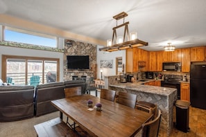 A modern kitchen with a stone wall, wooden cabinets, and a built-in island. - Ski-in/ski-out home with pool, hot tub, sauna, washer/dryer, & private balcony (Keystone)