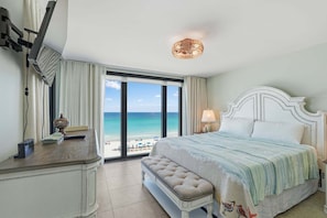 A hotel room with a large window, a bed, a desk, and a chair. - Watercrest 603 - Free Beach Chairs! (Panama City)