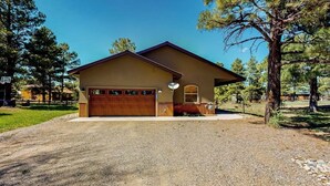 A single-story house with a garage, a satellite dish, and a well-maintained lawn. - Inviting home with hot tub, fireplace & enclosed yard - near trails & dining (Pagosa Springs)