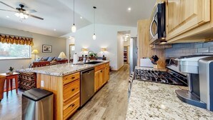 A modern kitchen with wooden cabinets, granite countertops, a built-in oven, and a central island with seating. - Inviting home with hot tub, fireplace & enclosed yard - near trails & dining (Pagosa Springs)