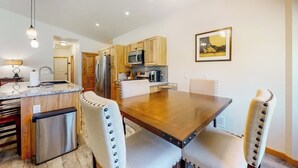 A modern kitchen with wooden cabinets, a built-in microwave, and a dining area with a wooden table and upholstered chairs. - Inviting home with hot tub, fireplace & enclosed yard - near trails & dining (Pagosa Springs)