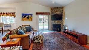 A living room with a sofa, ottoman, and a fireplace. - Inviting home with hot tub, fireplace & enclosed yard - near trails & dining (Pagosa Springs)