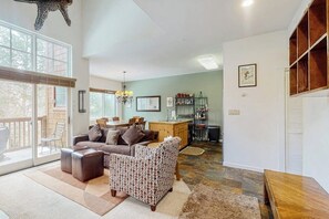 A spacious living area with a sofa, armchair, and ottoman, a dining table, and a kitchen area with a countertop and cabinets. - Gorgeous mountain condo with fireplace, scenic balcony, walk-in shower, & W/D (Keystone)