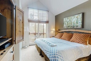 A bedroom with a bed, a TV, a window with blinds, and a painting on the wall. - Gorgeous mountain condo with fireplace, scenic balcony, walk-in shower, & W/D (Keystone)