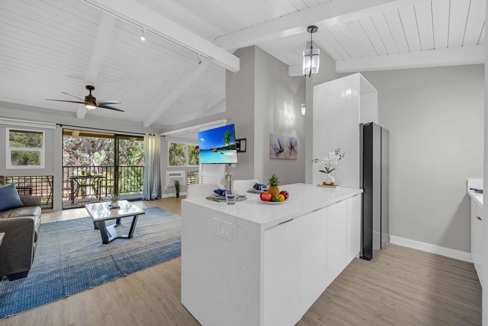 Una cocina moderna con una isla grande, un comedor con sofá y vistas al exterior.