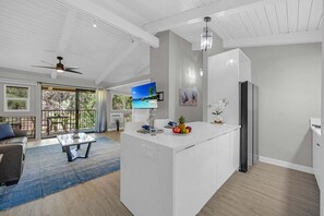 Eine moderne Küche mit einer großen Kochinsel, einem Essbereich mit einer Couch und Blick ins Freie.