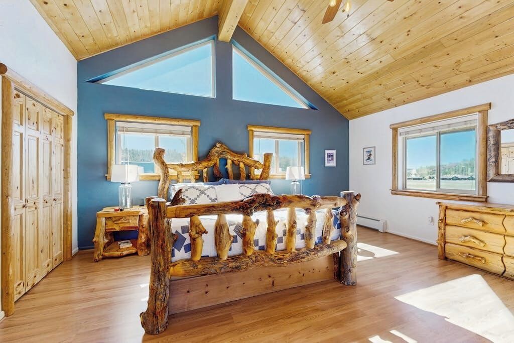 Une chambre avec un plafond en pente, des meubles en bois et de grandes fenêtres.