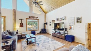 Ein geräumiges Wohnzimmer mit Kamin, Fernseher und Kunstwerken an den Wänden.