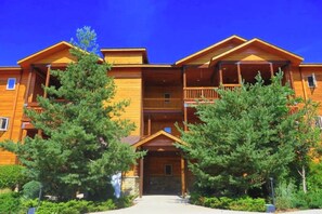 Un edificio in legno a più piani con balconi, circondato da alberi.