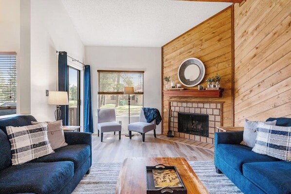 A living room with two sofas, a coffee table, a fireplace, and a large window. - Family-Friendly Condo w/ High-Speed WiFi, Washer/Dryer, & Central AC (Pagosa Springs)