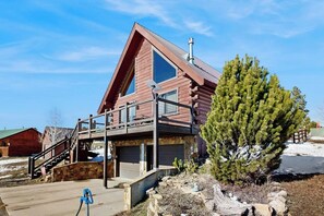 A log cabin with a balcony, a staircase, and a stone wall. - Cozy modern cabin with private hot tub, grill, deck, balcony, & W/D (Pagosa Springs)