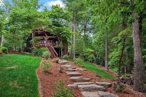 A wooden staircase leading to a covered wooden structure in a forested area.