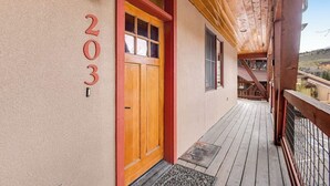 En träveranda med en röd dörr och siffran ’203’ på väggen.