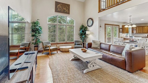 A spacious living area with a high ceiling, a dining area, and a kitchen. - Comfortable home with large deck, fully stocked kitchen, wifi & great location (Pagosa Springs)