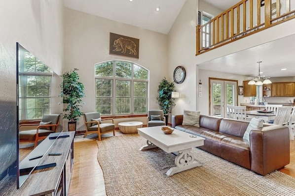 A spacious living area with a high ceiling, a dining area, and a kitchen.