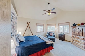 Une chambre à coucher avec un lit, un ventilateur de plafond, une commode et une chaise.