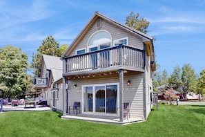 A two-story house with a balcony, large sliding glass doors, and a deck with outdoor furniture. - Stunning lake house with dock, firepit, grill, canoes, & mountain views (Pagosa Springs)