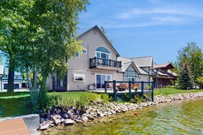 Ein großes Haus mit Balkon, Teich und gepflegtem Rasen.