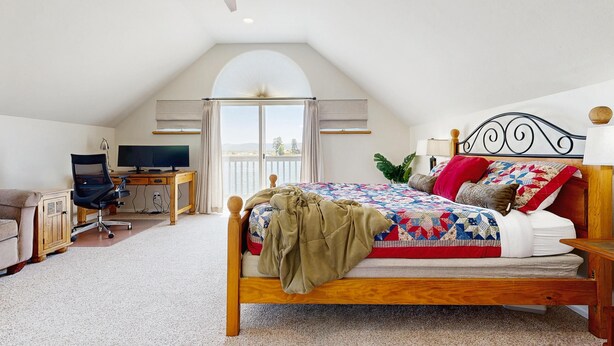 Una camera da letto con un letto, una scrivania, una sedia e una ventola a soffitto.
