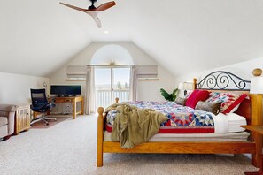 Ein Schlafzimmer mit einem Bett, Schreibtisch, Stuhl und Deckenventilator.