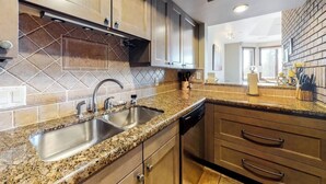 A kitchen with granite countertops, stainless steel sink, and wooden cabinets. - Meadows Clarion 2, Mountainview condo w/ three fireplaces, shared pool and hot tub & winter shuttle (Steamboat Springs)