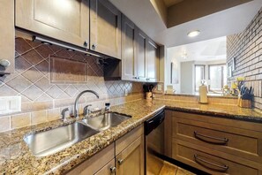 Eine Küche mit Granit Arbeitsplatten, Spüle aus Edelstahl und Holzschränken.