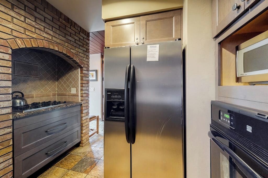 A kitchen with a brick wall, stainless steel appliances, and a microwave.
