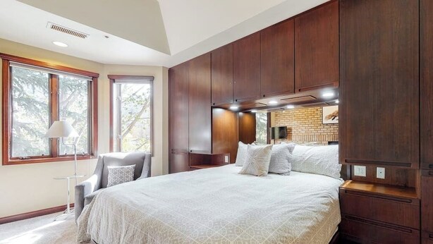 A bedroom with a large bed, wooden cabinetry, a desk, and a chair. - Meadows Clarion 2, Mountainview condo w/ three fireplaces, shared pool and hot tub & winter shuttle (Steamboat Springs)
