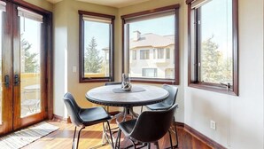 A corner room with a round table and four chairs, large windows, and a view of a building. - Meadows Clarion 2, Mountainview condo w/ three fireplaces, shared pool and hot tub & winter shuttle (Steamboat Springs)