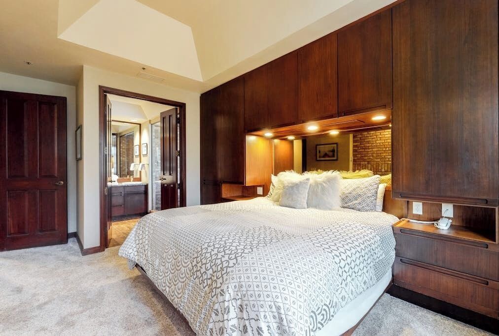 Une chambre avec un grand lit, une armoire en bois et un miroir.