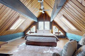 A high-ceilinged attic bedroom with a large bed, a ceiling fan, and skylights. - Charming mountain home with hot tub, views, and cozy fireplace (Vail)