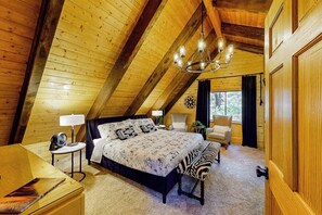 Ein Schlafzimmer mit schrägem Dach, einem Bett, einem Schreibtisch, einem Sessel und einer Sitzbank mit ZEBRA-Muster.