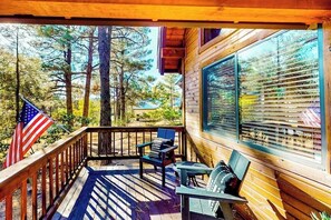 Eine Holzterrasse mit Blick auf Bäume, eine amerikanische Flagge und ein Fenster mit Jalousien.