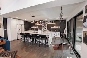 A modern kitchen with a central island, pendant lighting, and a hanging chair. - Charming Vail House with Cozy Fireplace, Jetted Tub & Scenic Mountain Views (Vail)