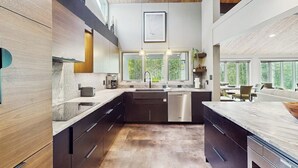 Una cocina moderna con armarios oscuros, una isla central y un amplio ventanal que proporciona luz natural.