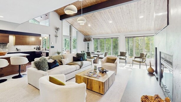 Un salón amplio con techos altos, ventanas grandes y muebles modernos.